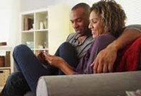 A couple sitting on a couch and smiling together.