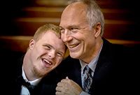 Down Syndrome Boy Resting Head on Shoulder of His Father