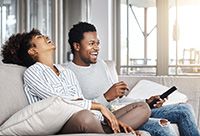 A happy couple laughing together on the couch.
