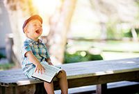 A gleeful boy with Down syndrome holding an open book of scripture.