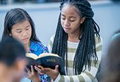 Two teenaged girls reading The Holy Bible.
