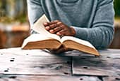 Person reading scriptures sitting at wooden table