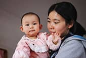 Woman holds baby in pink clothing