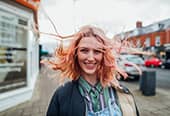 Woman standing outdoors looking away from the camera while her hair blows in the wind