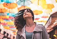 Woman walking down an alley with a bunch of umbrellas strung between the buildings.