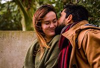 Photo of a young adult man kissing his girlfriend's cheek