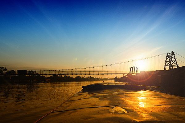 sunset behind bridge over water