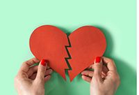 Hands holding a broken paper heart