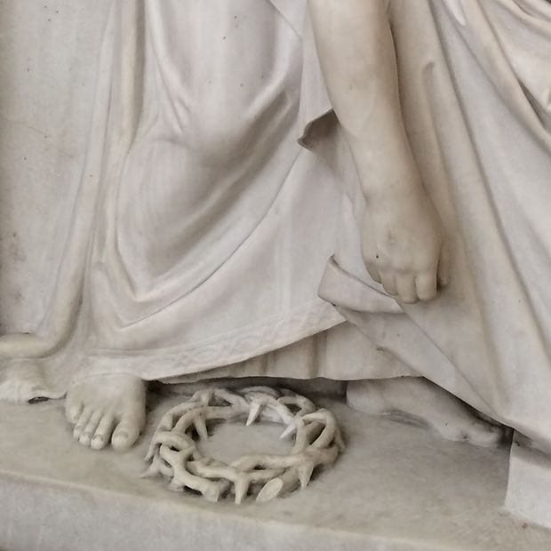 Statue of Jesus Christ reaching toward the ground for His crown of thorns—one of the many adversities that He faced.